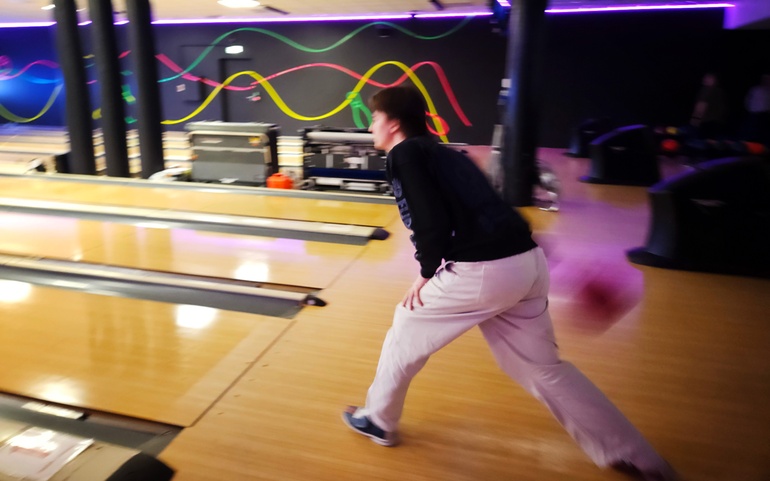 Ung mann i ferd med å kaste en bowlingkule.
