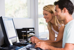 Dame og mann sitter ved en PC