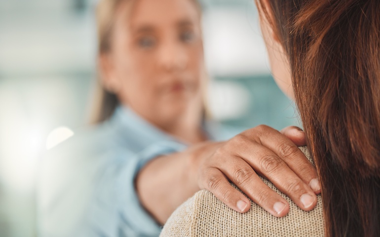 Empati - kvinne legger hånden på skulderen til annen kvinne, som har ryggen til