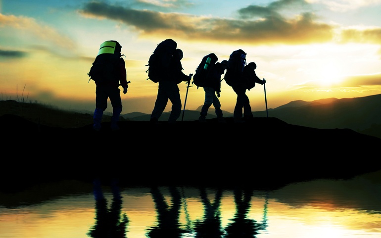 Siluetter av mennesker på tur i solnedgang