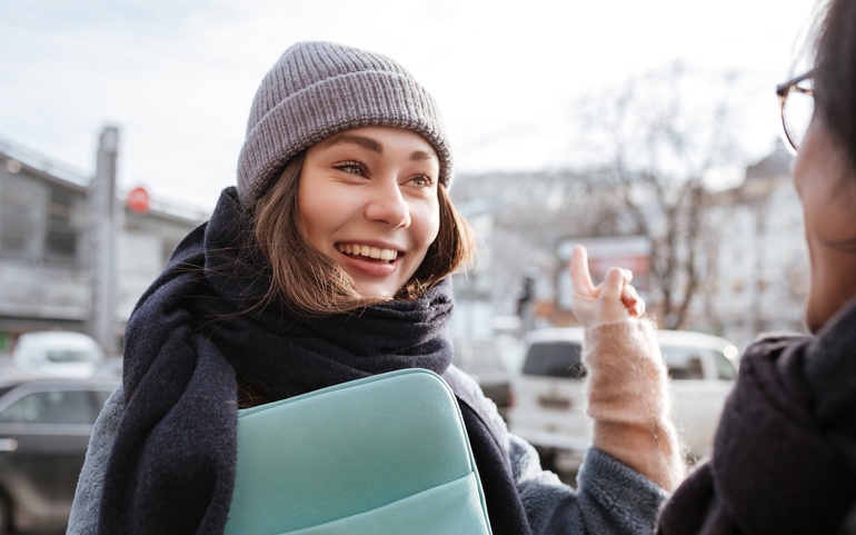 Dame som smiler og peker mot en bygning