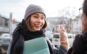 Dame som smiler og peker mot en bygning