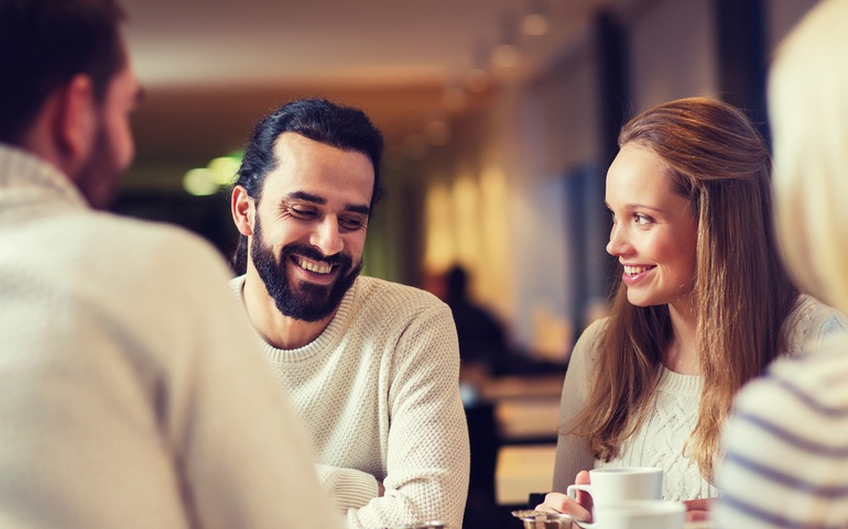 En gruppe personer sitter rundt et bord. Fokuset er på en mann og en kvinne midt i bil