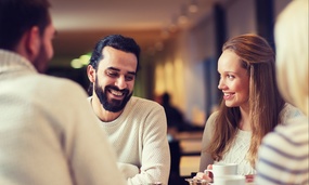 En gruppe personer sitter rundt et bord. Fokuset er på en mann og en kvinne midt i bil