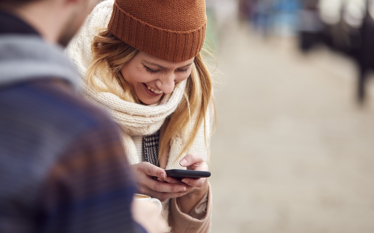 En dame ser blid ned på mobiltelefonen sin