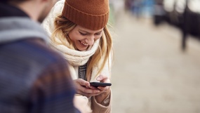 En dame ser blid ned på mobiltelefonen sin