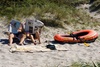 To menn leser aviser på ei strand