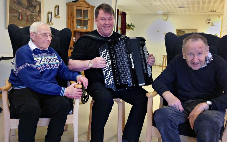 Musikklærer Truls Barnung spiller for to eldre menn