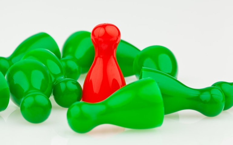 En rød stående spillbrikke/menneske i en samling grønne liggende