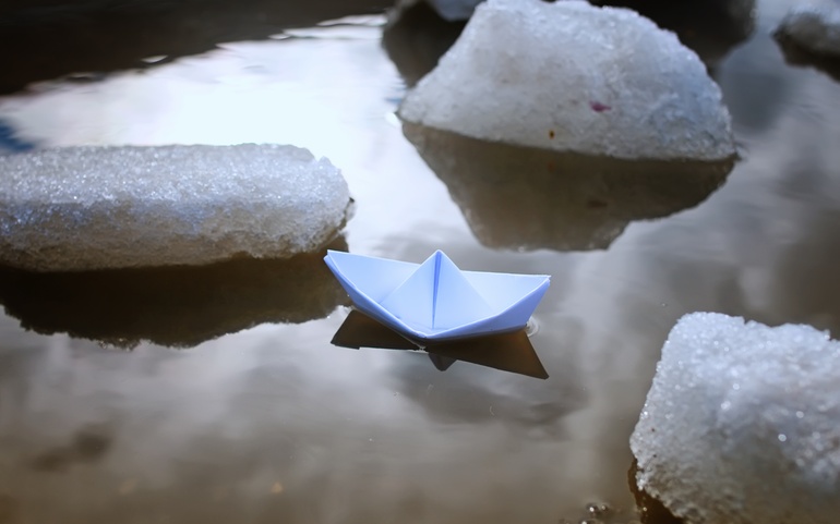 Papirbåt flytende mellom smeltende snø